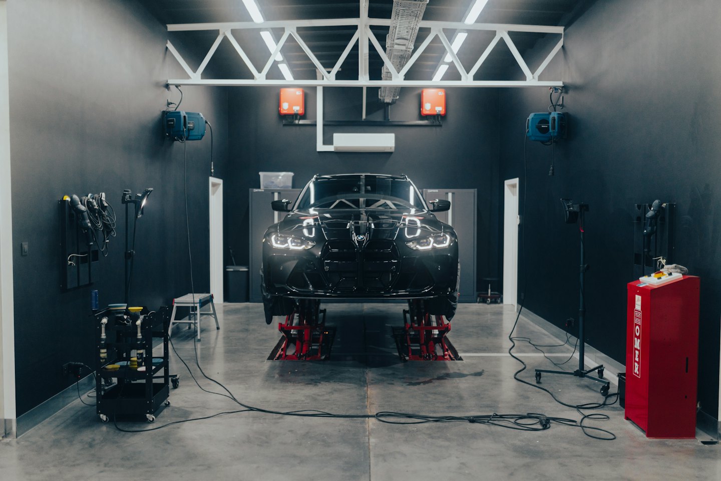 Auto di lusso nera su ponte sollevatore in un'officina.